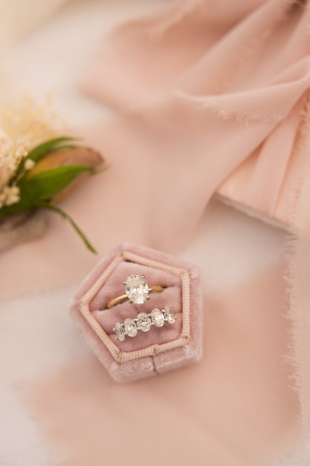 bride engagement ring and wedding band on a pink velvet box