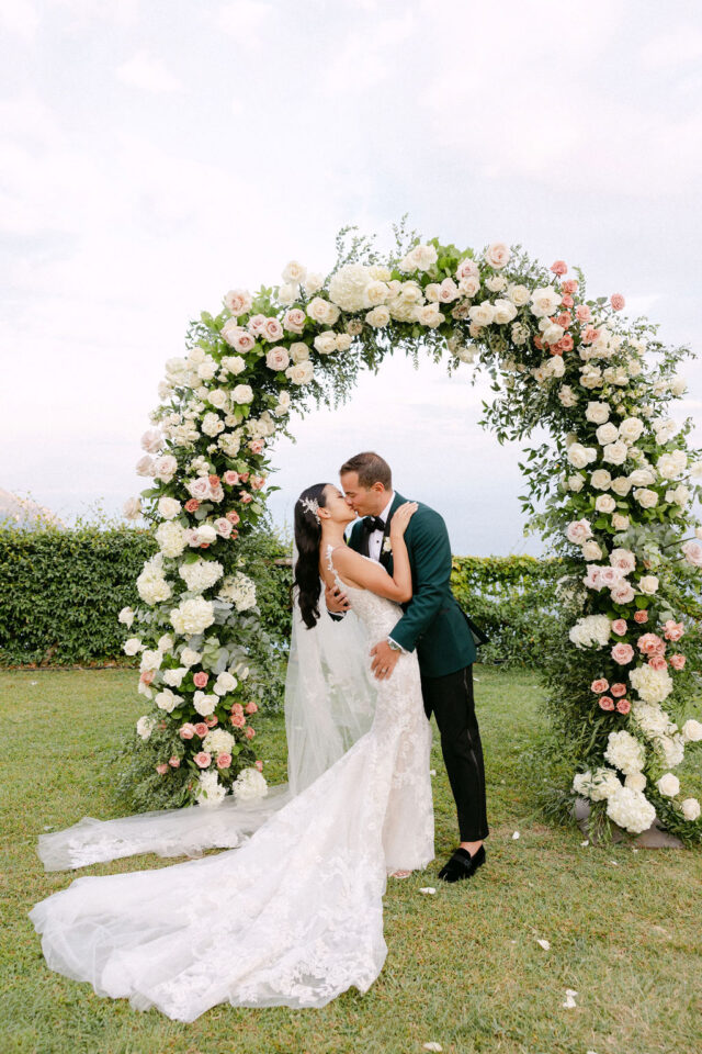 Birde and Groom kissing under the wedding flowers arch