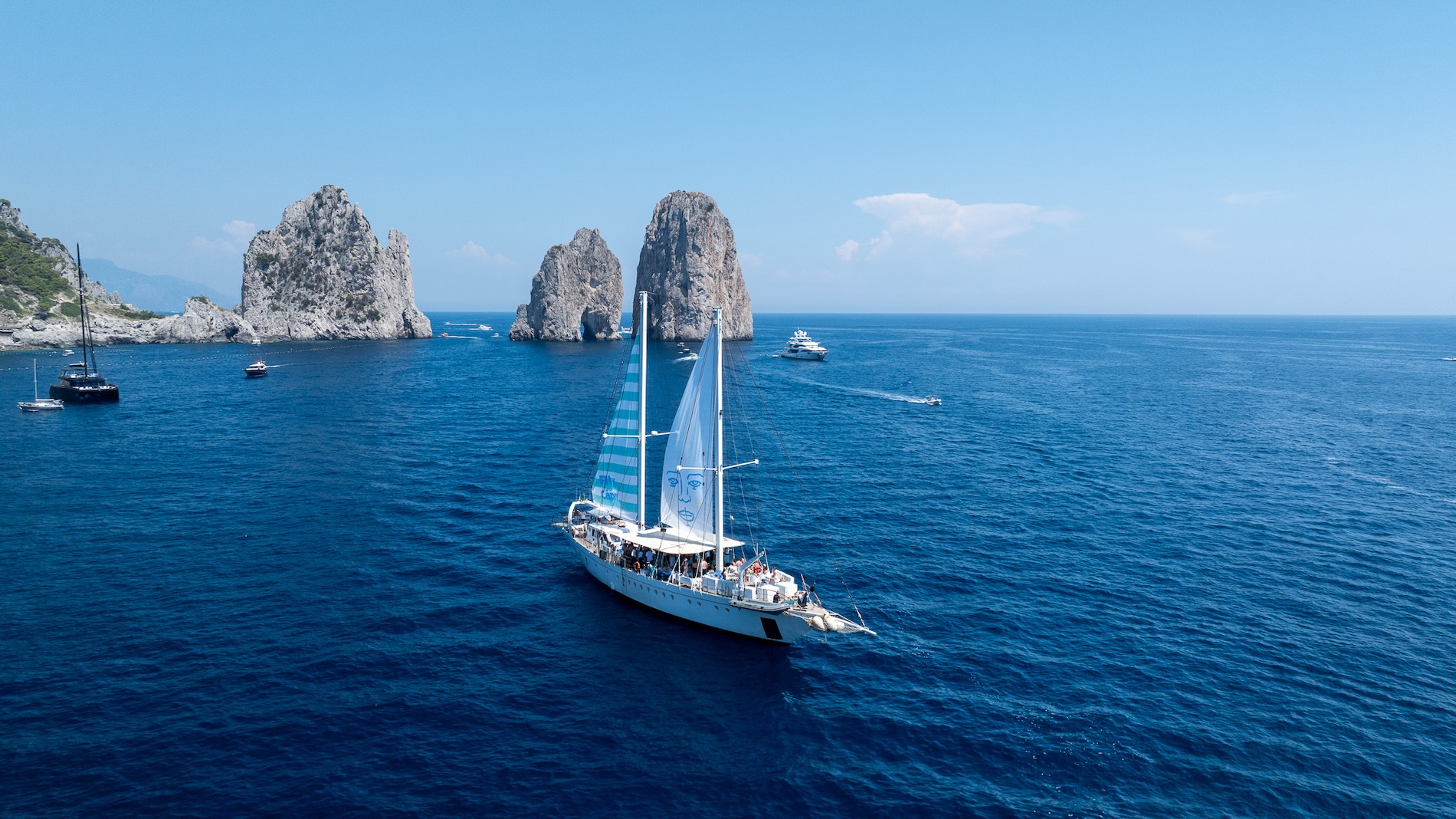 Sailing boat in Capri with Faraglioni rocks the background